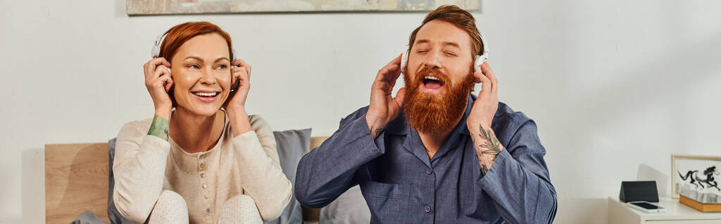 day off without kids, enjoyment, shared music, redhead husband and wife, happy couple in wireless headphones, bearded man and carefree woman, tattooed music lovers, weekends relaxation, banner  - Photo, Image