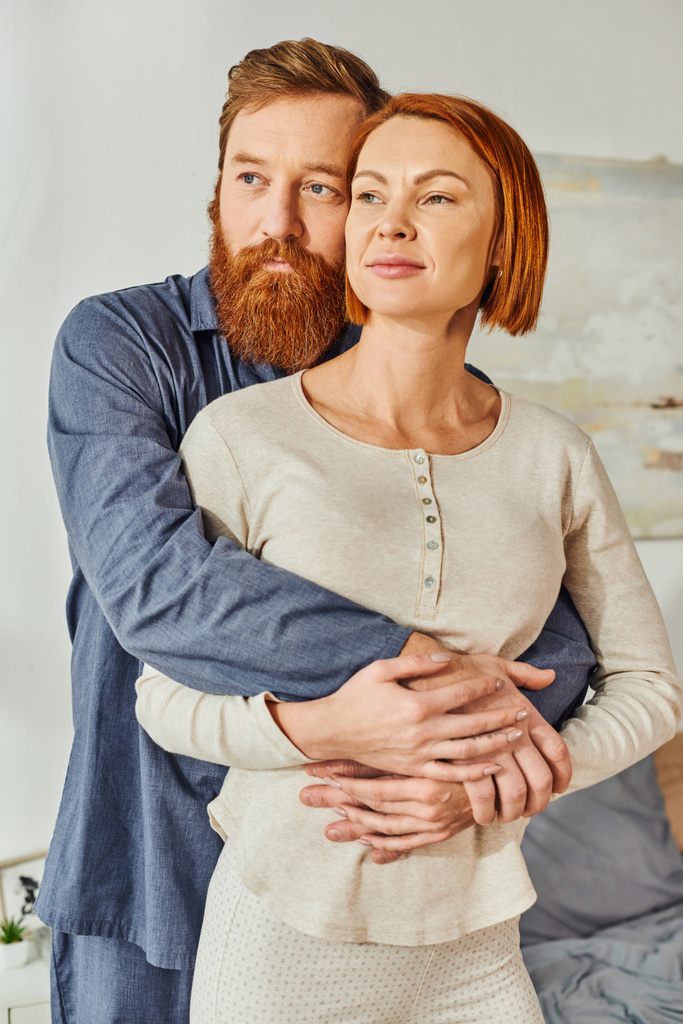married couple hugging in cozy bedroom, day off without kids, redhead husband and wife, enjoying time together, weekends together, tattooed, bonding, love, parents alone at home - Photo, Image