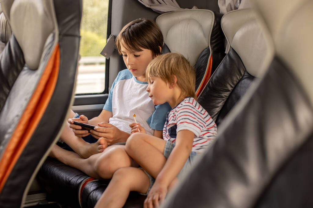 Діти, брати і сестри, грають на мобільному телефоні під час подорожі з автобусом у довгій подорожі, сімейні канікули
 - Фото, зображення