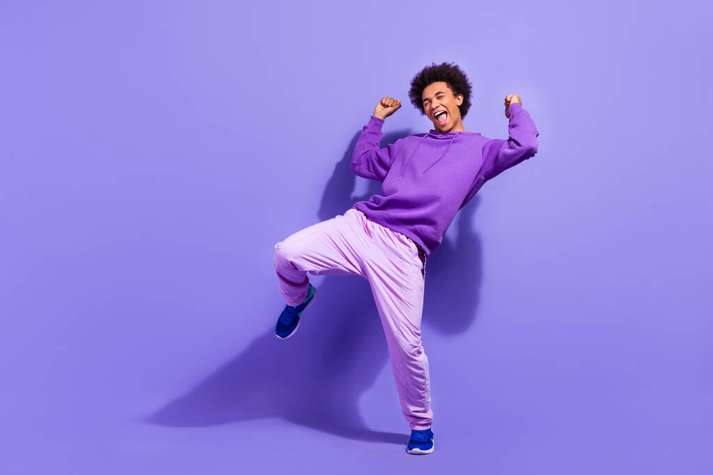 Повна довжина фото екстатичного божевільного хлопця з афро зачіски одягнений фіолетовий пуловер святкувати виграшну гру ізольовано на фіолетовому кольоровому фоні
. - Фото, зображення