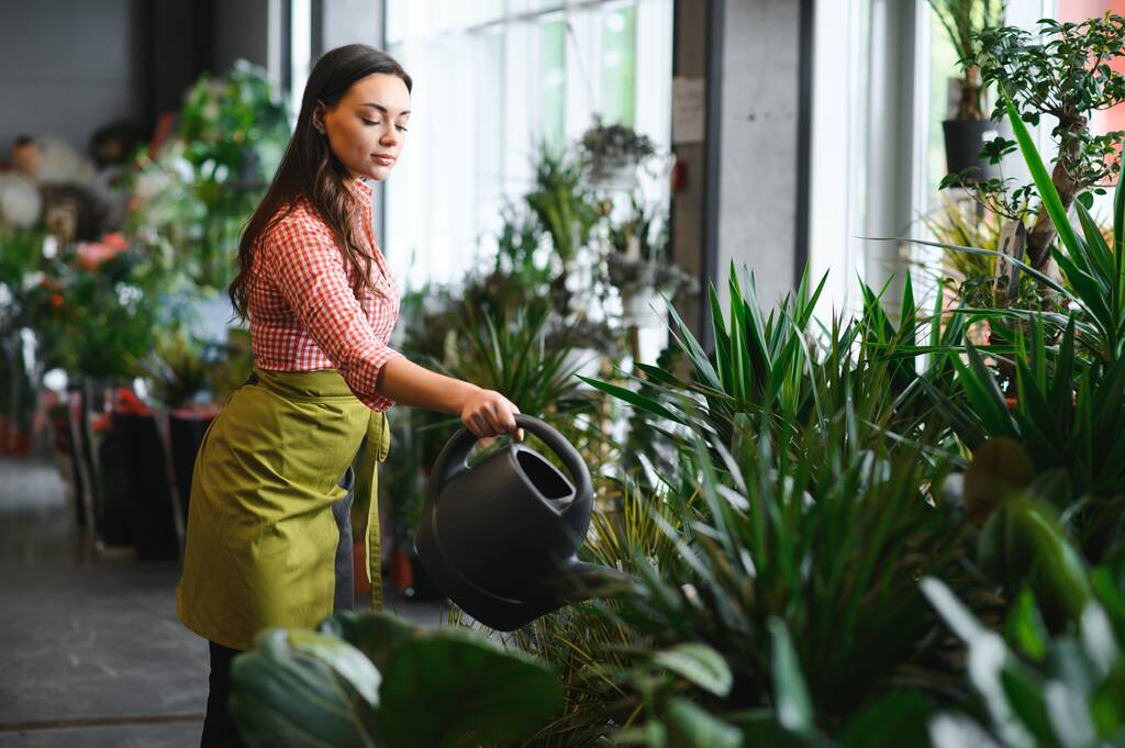 Woman florist working at her flower shop standing surrounded by plants. - Photo, Image