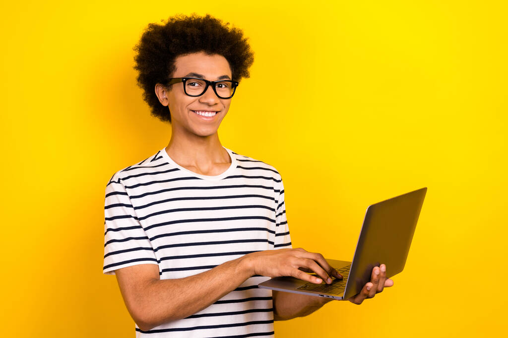 Zdjęcie młodego mądrego stażysty junior trzymać laptop nosić okulary koder nauki stać się ekspertem izolowane na żółtym tle kolor. - Zdjęcie, obraz