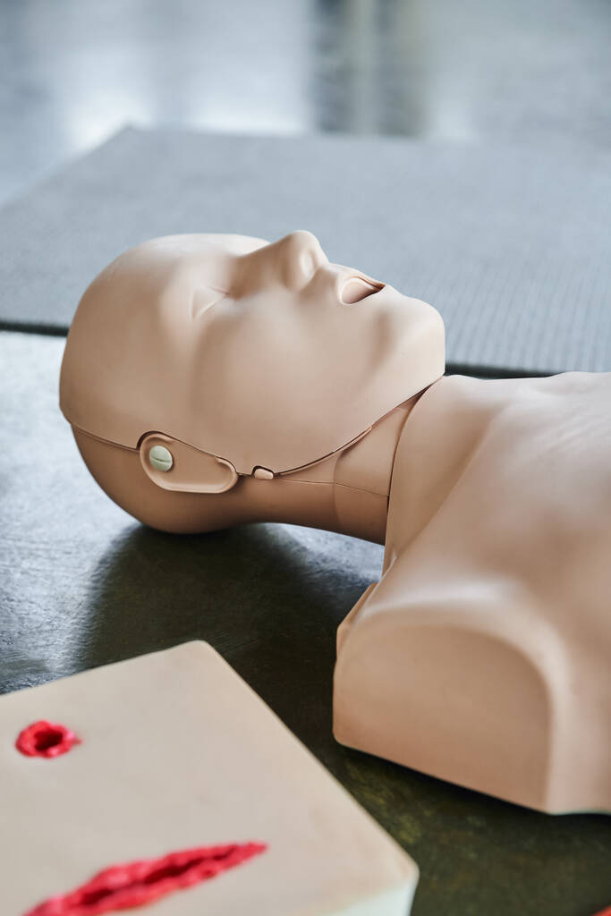 kardiopulmonální resuscitační cvičení figuríny v blízkosti simulátoru péče o rány na podlaze ve výcvikové místnosti, lékařské vybavení pro výcvik první pomoci a rozvoj dovedností - Fotografie, Obrázek