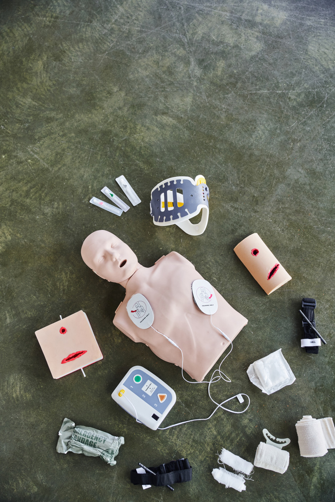 bovenaanzicht van reanimatiepop, automatische defibrillator, wondverzorgingssimulatoren, compressie tourniquets, nekbeugel en verband, medische apparatuur voor EHBO-training en ontwikkeling van vaardigheden - Foto, afbeelding