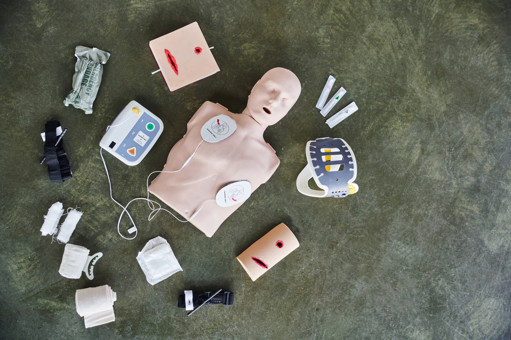 άνω όψη του ανδρεικέλου CPR, αυτόματος εξωτερικός απινιδωτής, προσομοιωτές περιποίησης πληγών, αιμοστατικοί επίδεσμοι, επίδεσμοι και σύριγγες, ιατρικός εξοπλισμός και έννοια εκπαίδευσης πρώτων βοηθειών - Φωτογραφία, εικόνα