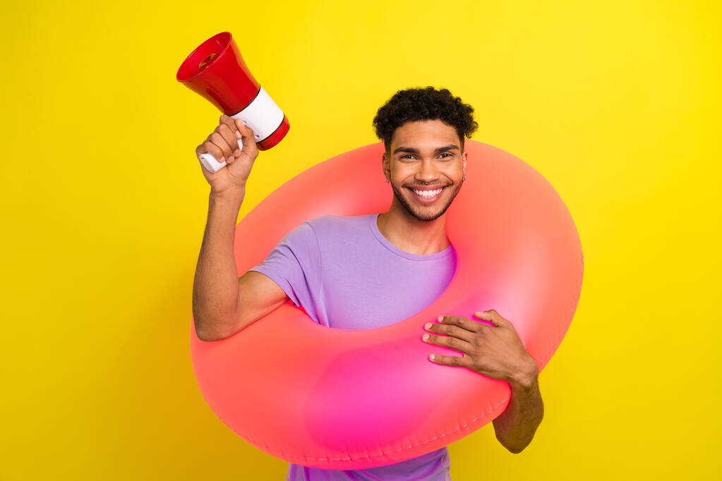 Portrait of cheerful handsome person hold inflatable circle loudspeaker toa isolated on yellow color background. - Photo, Image