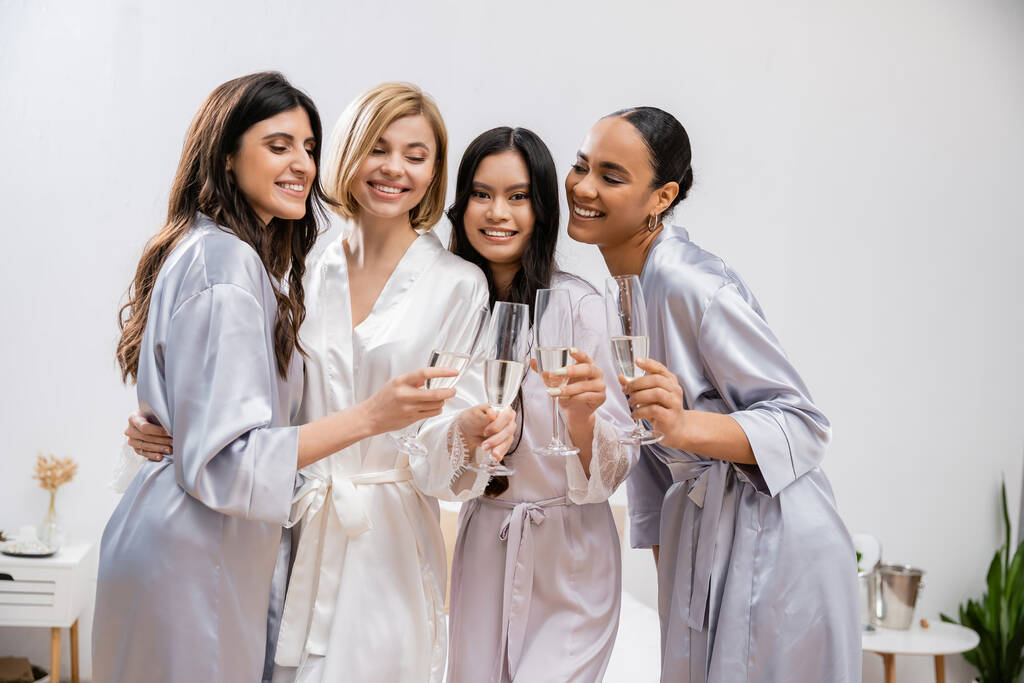 Brautparty, interrassische Freundinnen, die Gläser mit Champagner halten, Feier vor der Hochzeit, brünette und blonde Frauen, Braut und ihre Brautjungfern, verschiedene Ethnien, Positivität   - Foto, Bild