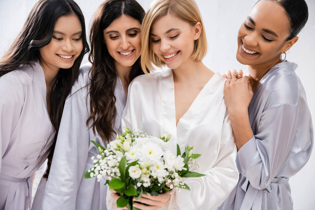 svatební sprcha, čtyři ženy, šťastná nevěsta držící kytici poblíž družiček v hedvábných šatech, kulturní rozmanitost, společně se pobavit, cíle přátelství, brunetky a blondýnky, úsměv a radost  - Fotografie, Obrázek