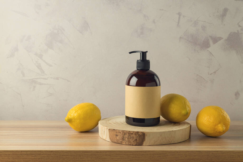 Ahşap masanın üzerinde limon özü olan şampuan ya da duş jeli şişesi. Paketleme tasarım arkaplanını düzenle - Fotoğraf, Görsel