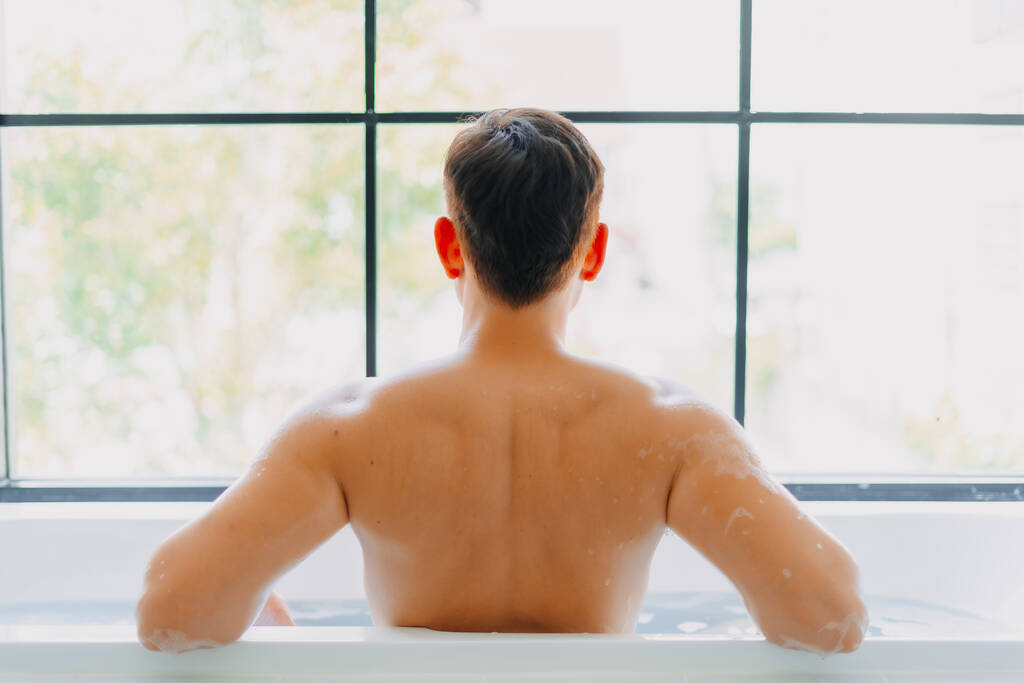 Zadní strana asijské muž sprchování ve vaně v koupelně. - Fotografie, Obrázek