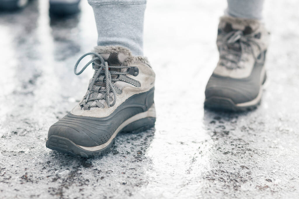 Χειμερινά παπούτσια στο παγωμένο πεζοδρόμιο. Επικίνδυνος καιρός. - Φωτογραφία, εικόνα