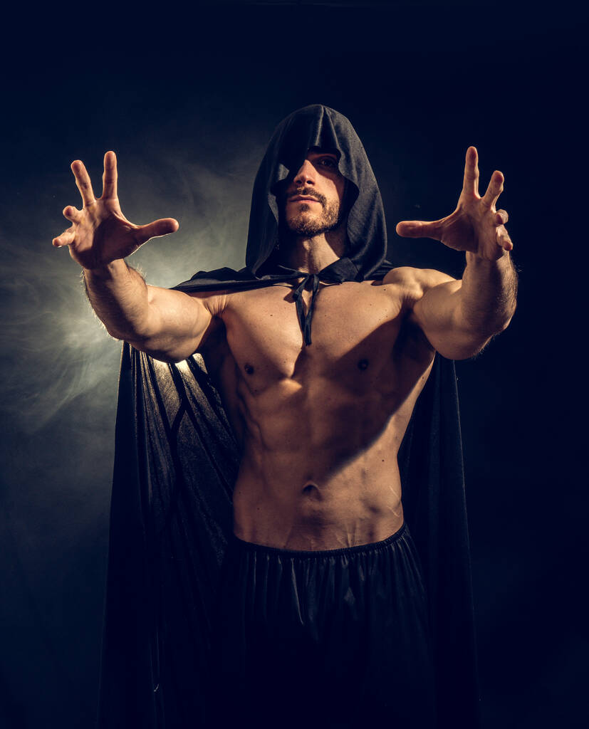 děsivé svalnatý mladík s špičatou stříšku a pláštěnku na nahé tělo - Fotografie, Obrázek