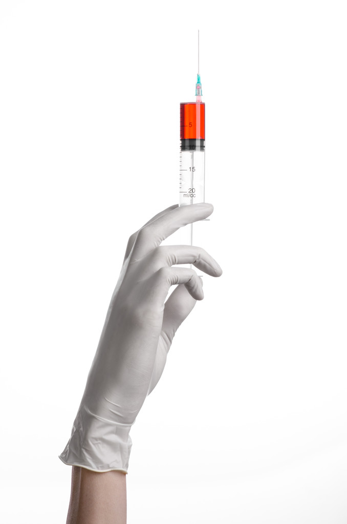 Doctor's hand met een injectiespuit, wit-gehandschoende hand, een grote spuit, medische kwestie, de arts maakt een injectie, witte achtergrond, geïsoleerde, witte handschoenen arts, ebola test, rode medicatie - Foto, afbeelding