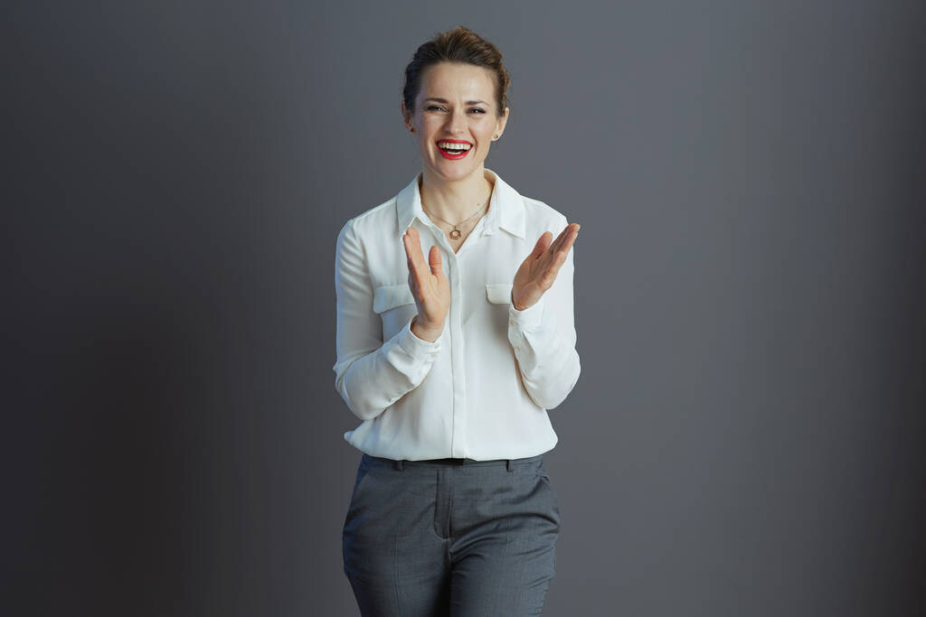 boldog elegáns kis üzlet tulajdonos nő fehér blúzban tapsol szürke háttér. - Fotó, kép