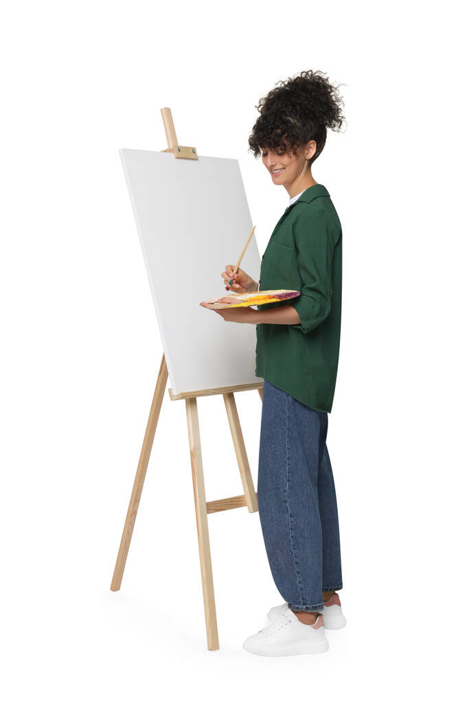 Jonge vrouw schilderen op ezel met doek tegen witte achtergrond - Foto, afbeelding