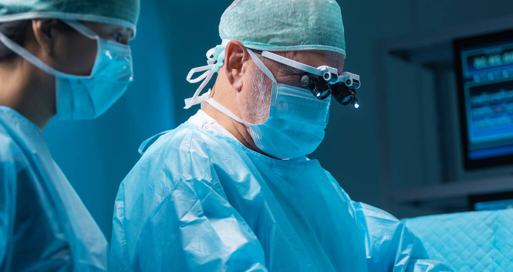Monipuolinen tiimi ammatti lääkärit suorittaa kirurgisen toimenpiteen nykyaikaisessa leikkaussalissa käyttäen korkean teknologian laitteita ja teknologiaa. Kirurgit yrittävät pelastaa potilaan sairaalassa. - Valokuva, kuva