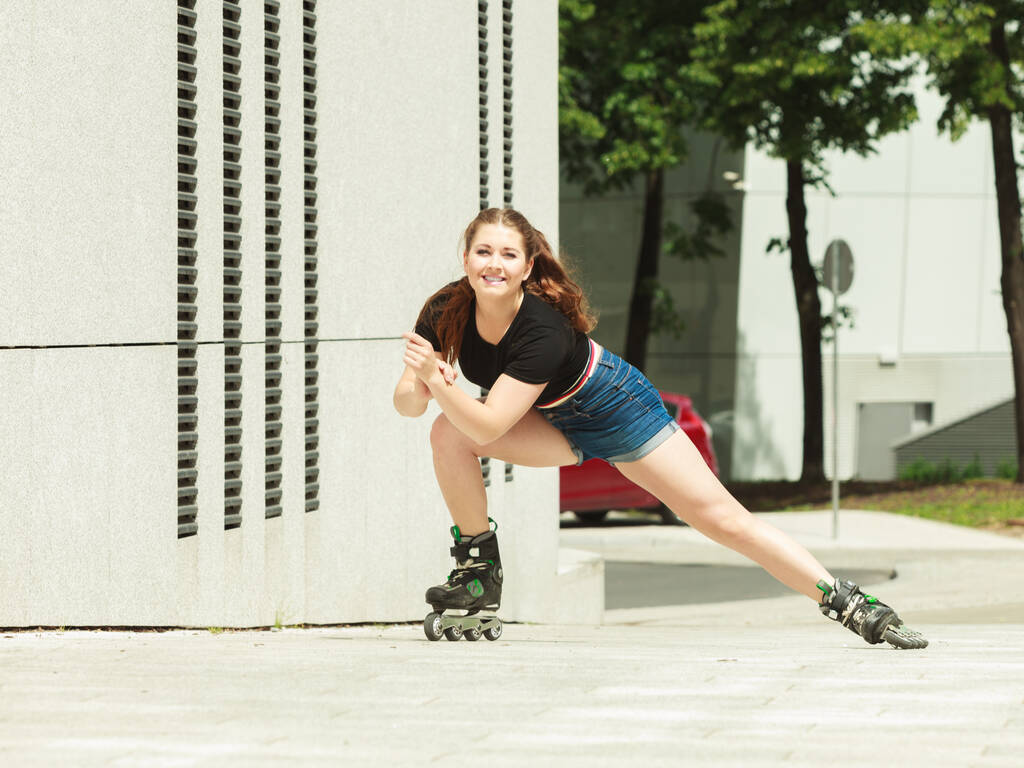 Mujer adolescente con patines de ruedas que monta rápido en la ciudad. Mujer siendo deportivo divirtiéndose durante el verano
. - Foto, imagen