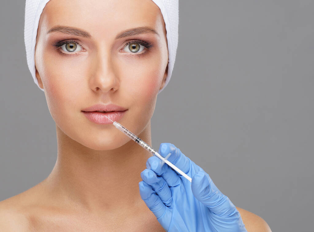 Az orvos egy fiatal nő gyönyörű arcát injekciózza be. Plasztikai sebészet, bőrfelvarrás és esztétikai orvoslás. - Fotó, kép