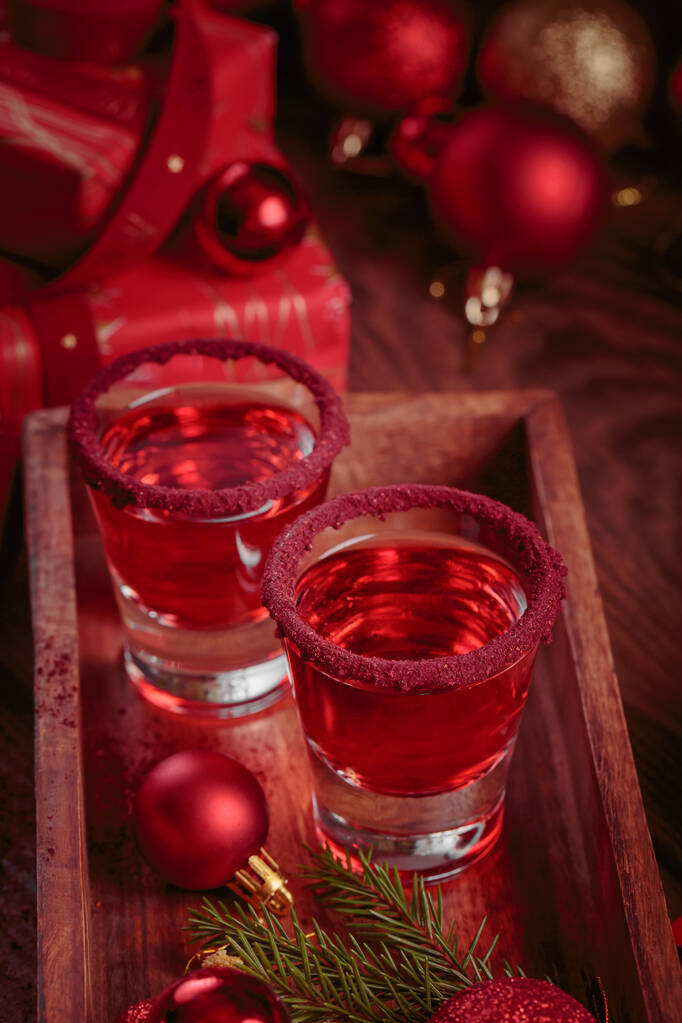 木製の背景に赤リキュールの2つのガラス。冬の休日や新年会のお祝いのコンセプト - 写真・画像