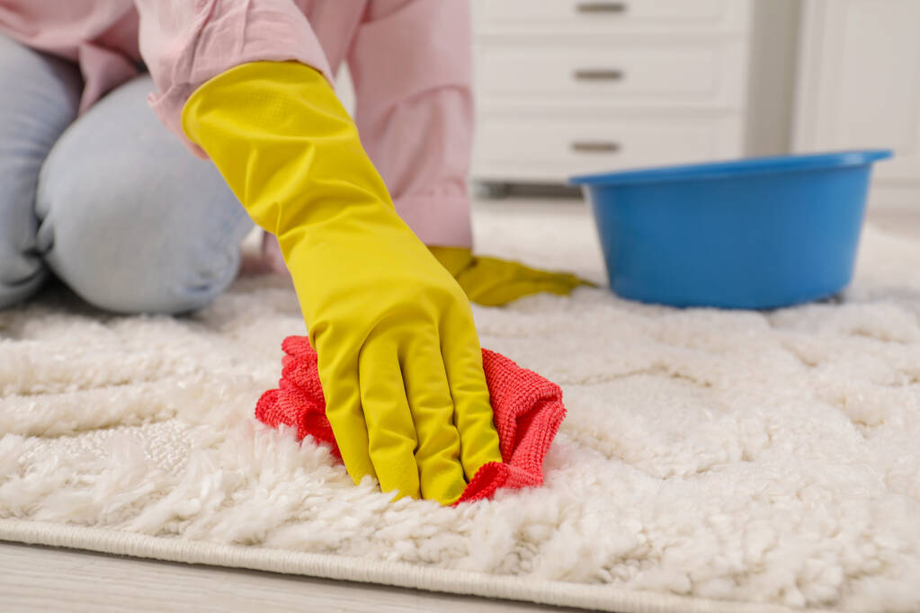 Femme en gants de caoutchouc nettoyage tapis avec chiffon à l'intérieur, gros plan. Espace pour le texte - Photo, image