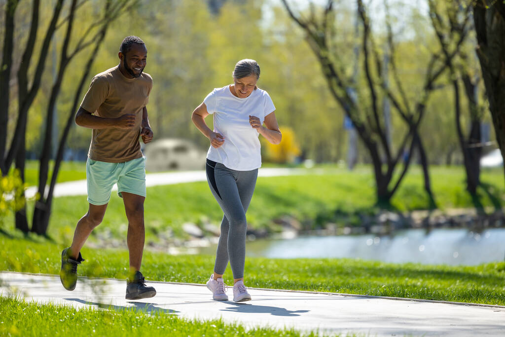 朝のランニング。男と女が公園で一緒に走る - 写真・画像
