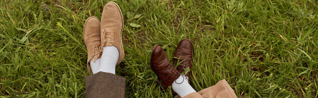Top kilátás lábak romantikus pár nadrág és vintage cipő ül együtt zöld füves réten, stílusos partnerek a vidéki menekülés, romantikus menekülés, banner - Fotó, kép