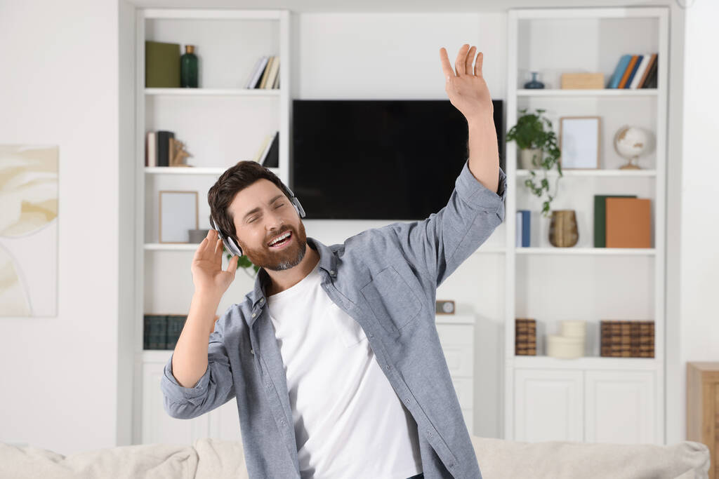 Συναισθηματικός άνθρωπος χορεύει ακούγοντας μουσική με ακουστικά στο σπίτι - Φωτογραφία, εικόνα