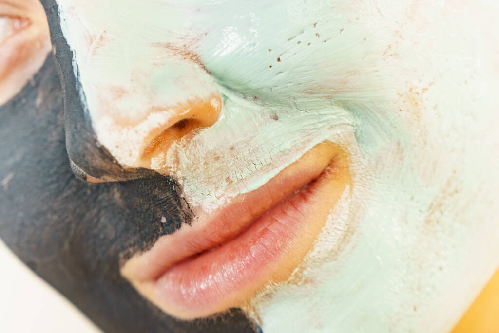 Kobieta czyści skórę, używając zielonego błota i czarnej maski. Dziewczyna dbająca o tłustą cerę. Zabiegi piękności. Skóra. - Zdjęcie, obraz