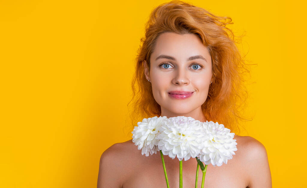 woman with womens day flowers in studio, copy space. woman with womens day flowers on background. woman with womens day chrysanthemum flowers. woman with womens day flowers isolated on yellow - Photo, Image