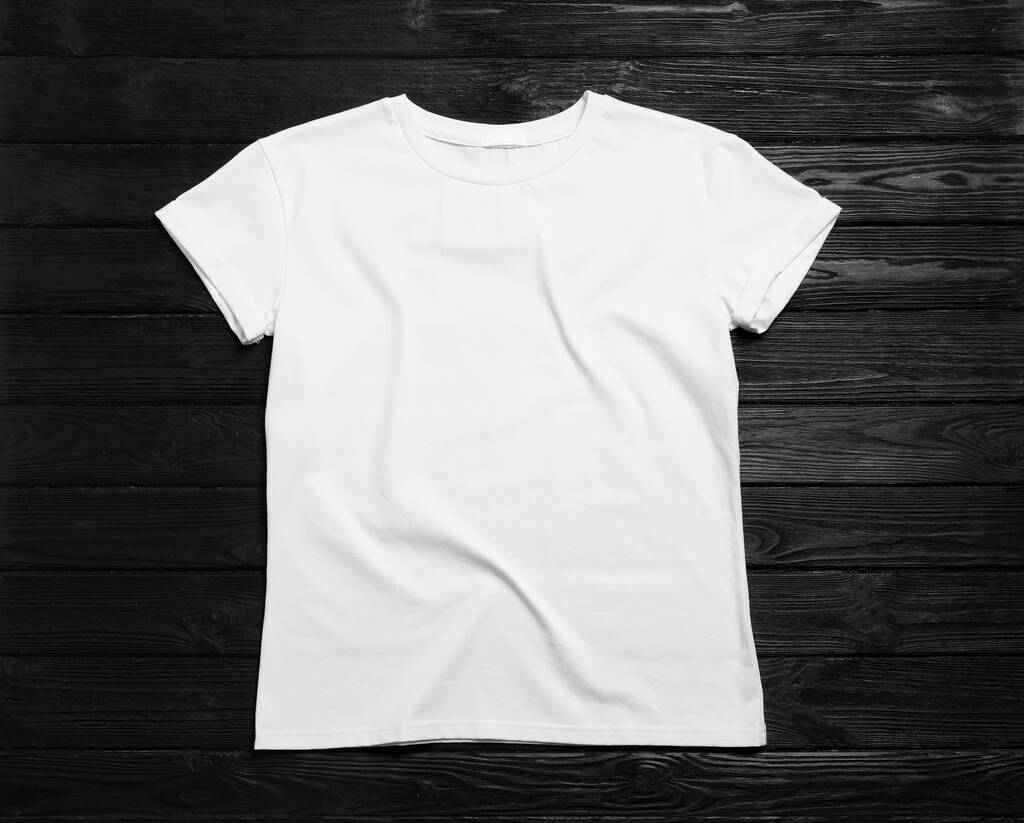 Stylowy biały t-shirt na czarnym drewnianym tle, widok z góry - Zdjęcie, obraz