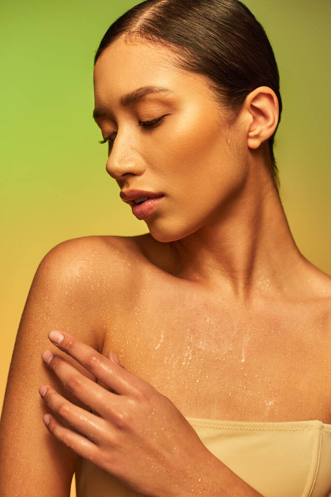 hydration, young asian woman with bare shoulders touching wet body and posing on gradient background, closed eyes, skincare campaign, beauty model, brunette hair, glowing skin  - Photo, Image