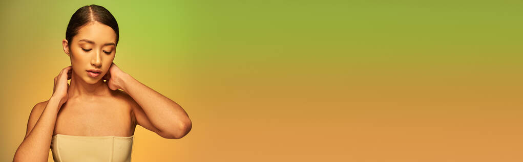 fotografía de belleza, mujer asiática con cabello moreno y hombros desnudos posando sobre fondo degradado, verde y naranja, cuidado de la piel, piel brillante, belleza natural, modelo joven, radiante, pancarta  - Foto, imagen