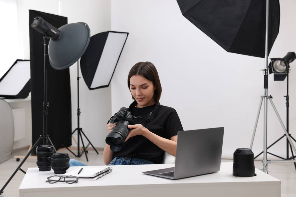 Fiatal professzionális fotós fényképezőgéppel az asztalnál a modern fotó stúdióban - Fotó, kép