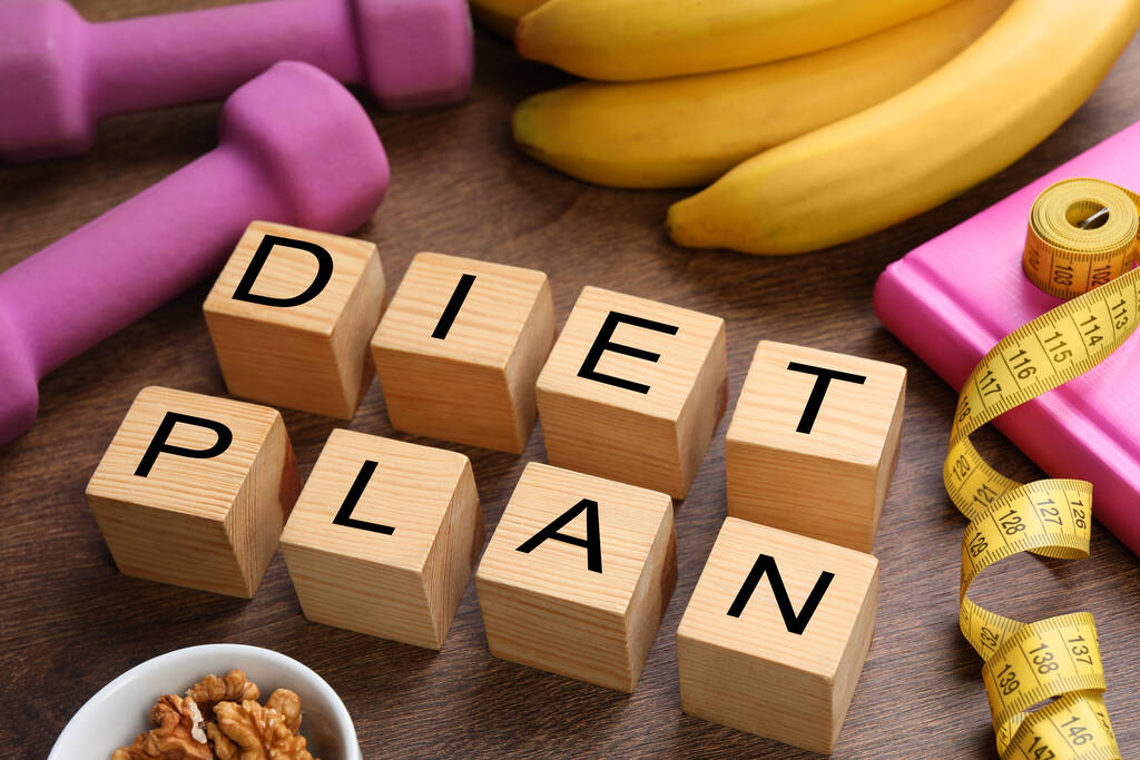 Phrase Diet Plan wykonany z kostek, przedmiotów fitness i produktów na drewnianym stole. Koncepcja odchudzania - Zdjęcie, obraz