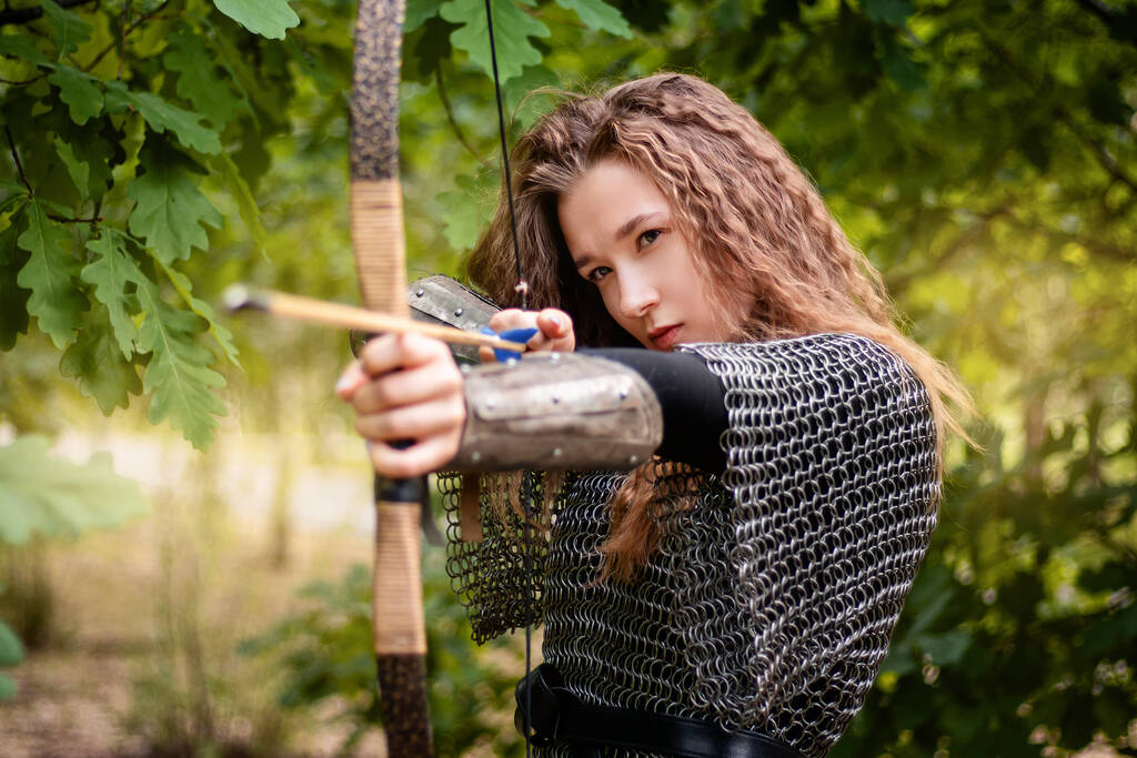 Ortaçağ savaşçısı kadın, zırhlı ve elinde yayıyla yaz ormanı zemininde.. - Fotoğraf, Görsel