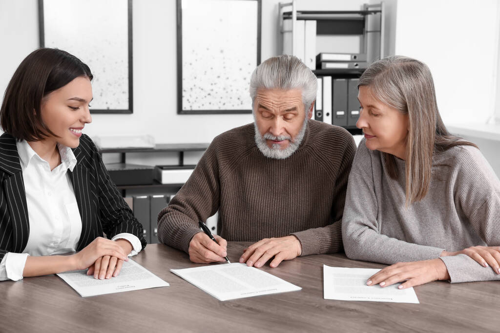 Elderly couple consulting insurance agent about pension plan at wooden table indoors - Photo, Image