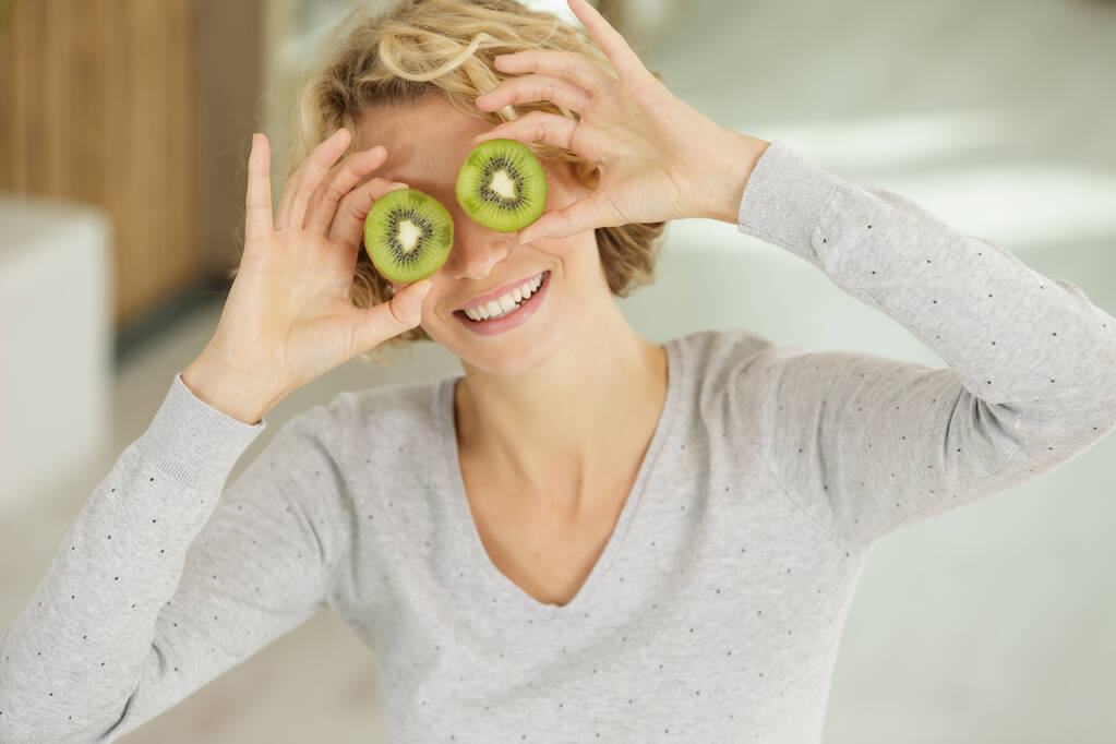 woman covering her eyes with kiwi slices - Fotografie, Obrázek