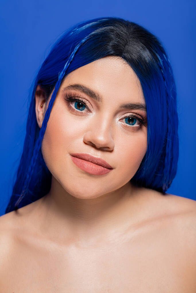 Gesichtspflege, hübsche junge Frau mit gefärbten Haaren posiert auf blauem Hintergrund, Haarfarbe, Individualismus, weibliches Model mit Make-up und trendiger Frisur, lebendige Jugend, Hautperfektion  - Foto, Bild
