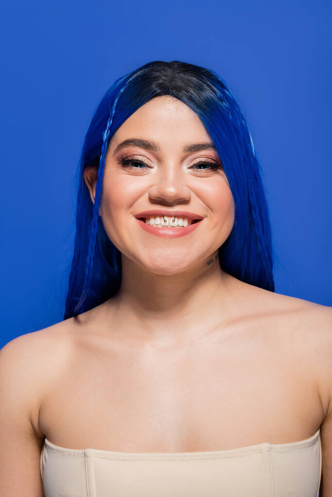 тренды красоты, счастливая молодая женщина с окрашенными волосами позирует на голубом фоне, цвет волос, индивидуализм, женская модель с макияжем и модной прической, яркая молодость, совершенство кожи, татуировка   - Фото, изображение