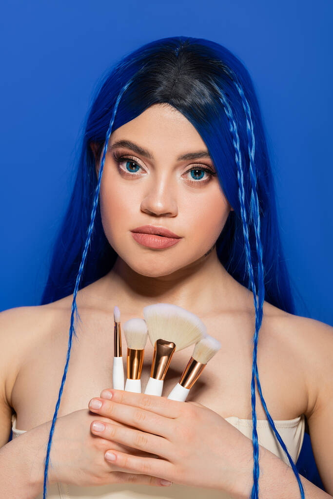 美容業界,個人主義,青の背景に化粧ブラシを保持しながら鮮やかな髪と目を持つ若い女性,化粧品,美容の傾向,画像,若者,自己表現  - 写真・画像