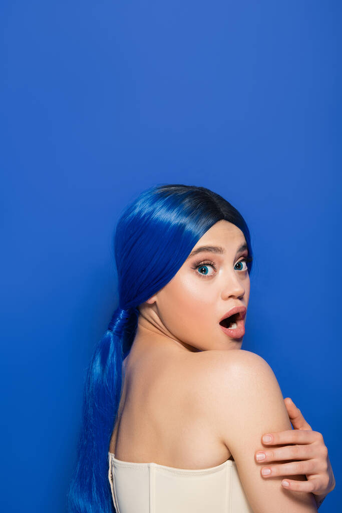 emotional model, portrait of shocked young woman with vibrant hair color posing with bare shoulders on blue background, youth, beauty trends, unique identity, banner - Photo, Image
