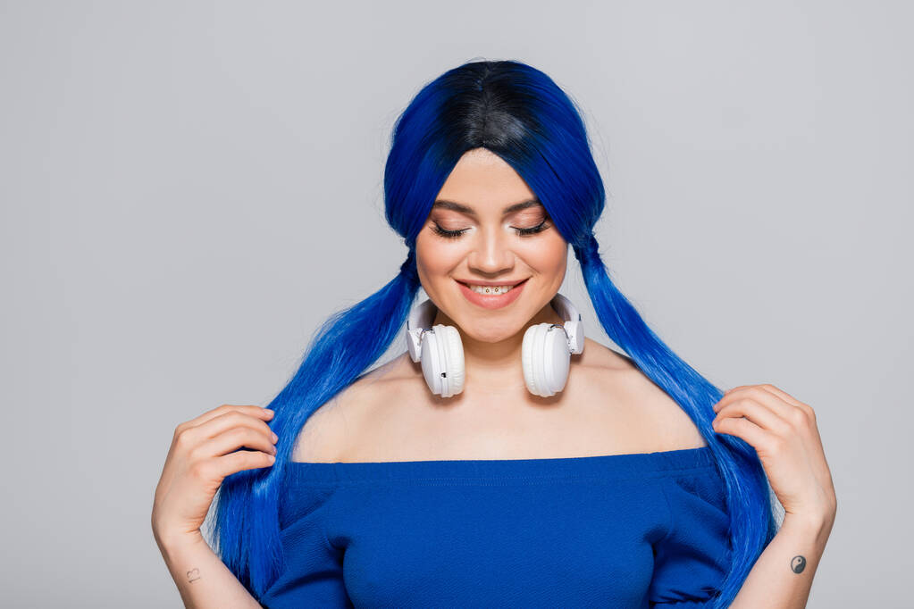 amante de la música, mujer joven feliz con el pelo azul y auriculares inalámbricos sonriendo sobre fondo gris, juventud vibrante, individualismo, subcultura moderna, auto expresión, tatuaje, sonido  - Foto, Imagen