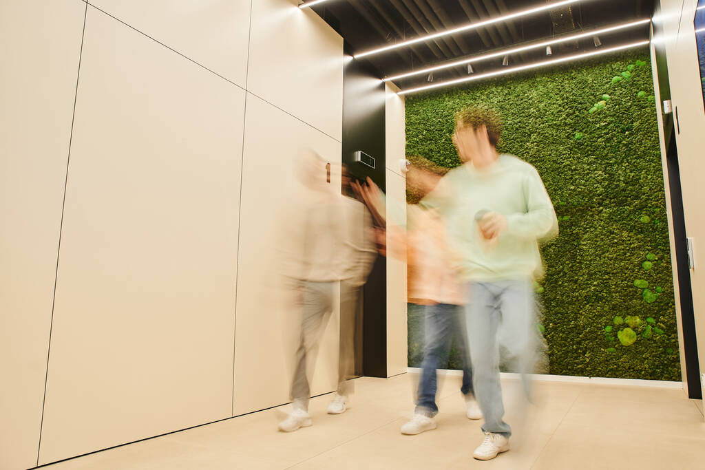 Длительное пребывание предпринимателей, идущих по коридору в коворкинг-офисе с современным интерьером и обсуждающих бизнес-проект, сотрудничество, партнерство и концепцию продуктивности - Фото, изображение