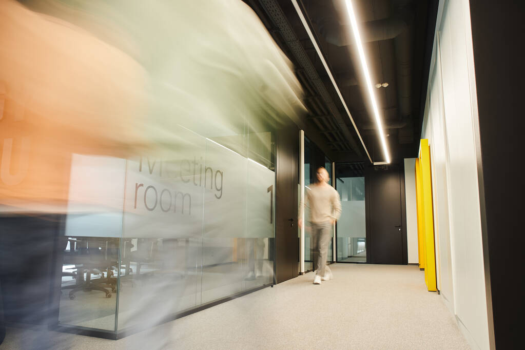 long exposure of energetic businessman walking along blurred meeting room in corridor of coworking environment in contemporary office, dynamic business concept - Photo, Image