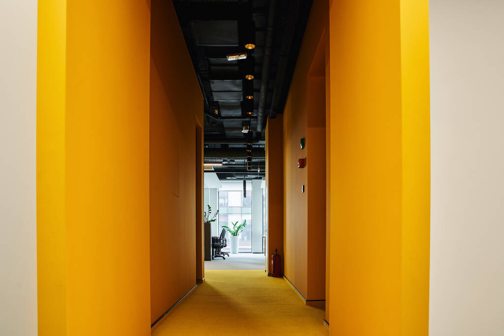 dlouhá chodba s malovanými stěnami v zářivě oranžové barvě v moderní kopracovní kanceláři s moderním high-tech stylem interiéru, koncept organizace pracovního prostoru - Fotografie, Obrázek