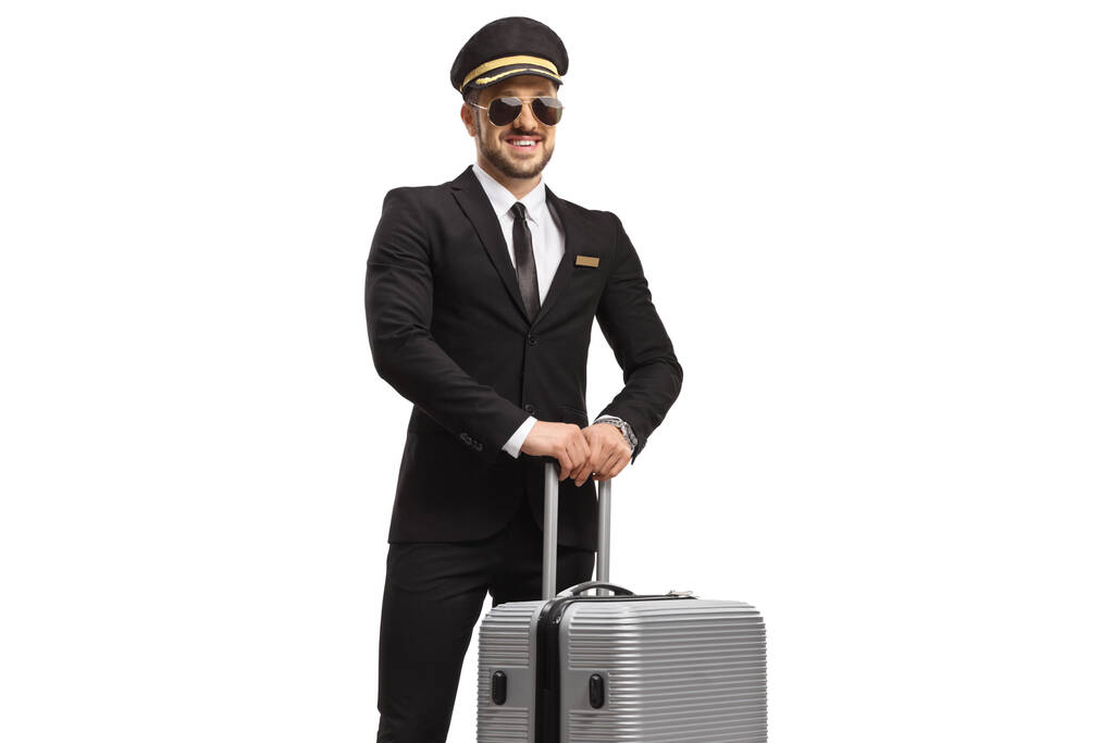 白い背景に隔離されたスーツケースでポーズをとるサングラスパイロット - 写真・画像