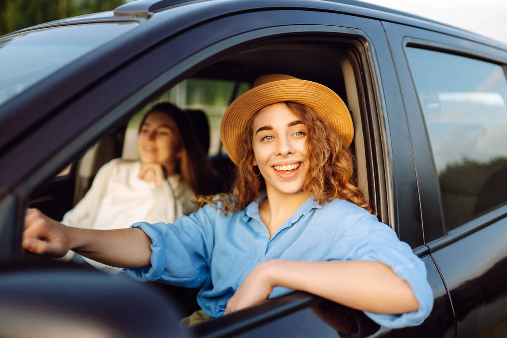 Две молодые женщины отдыхают и наслаждаются поездкой в машине, путешествием, концепцией образа жизни. Совместное использование автомобилей. - Фото, изображение