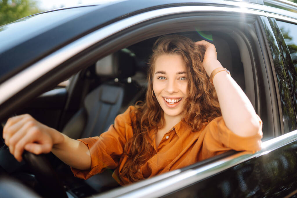 Lächelnde Frau am Steuer eines Autos. Junge Reisende am Steuer. Autofahren, Lifestylekonzept. - Foto, Bild