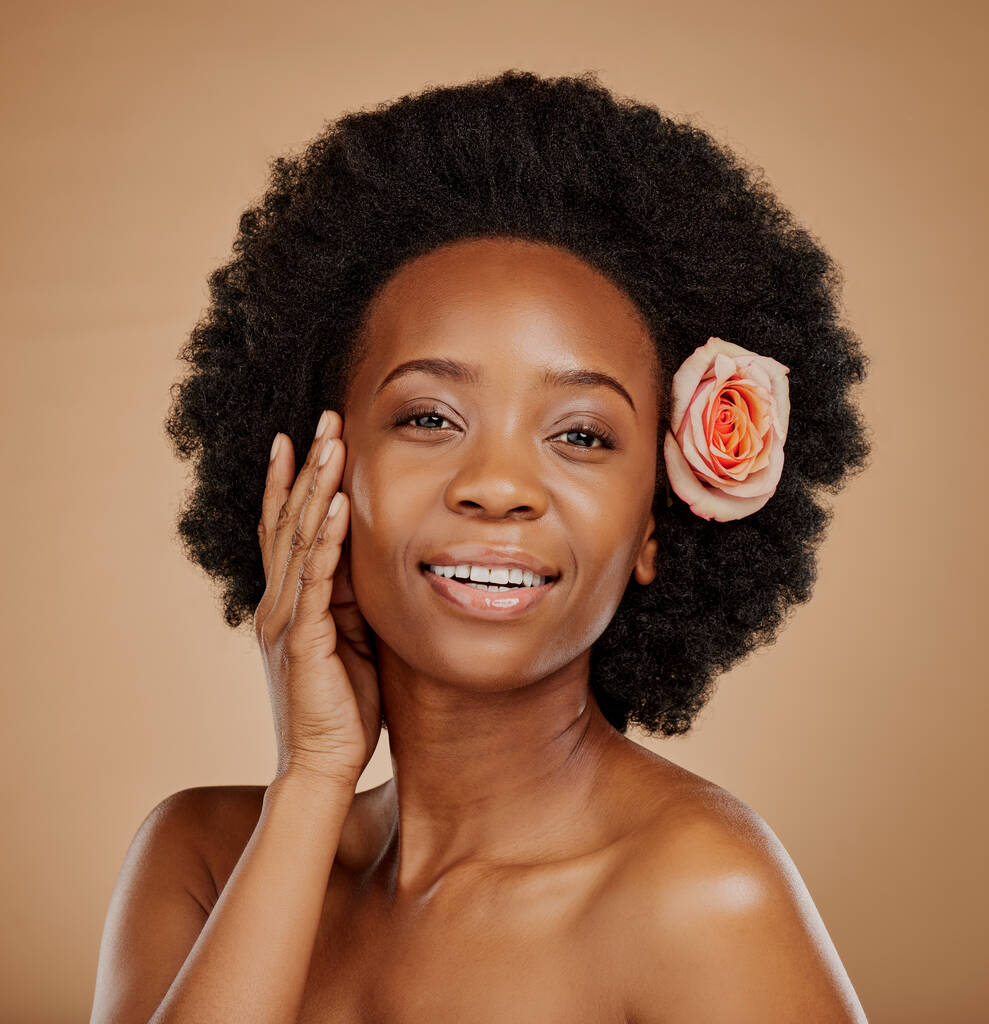 Donna nera, viso e cura della pelle con rosa in studio isolato su sfondo marrone. Ritratto, fiore e felice modello africano con cosmetici naturali, trattamento viso biologico e pianta di bellezza floreale - Foto, immagini