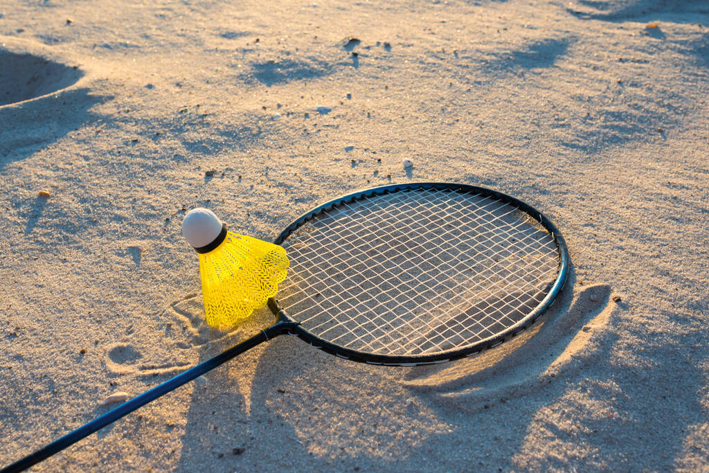 Outdoor sport spelletjes. Badminton racket en shuttlecock op het strand zand. Actieve gezonde levensstijl concep. - Foto, afbeelding
